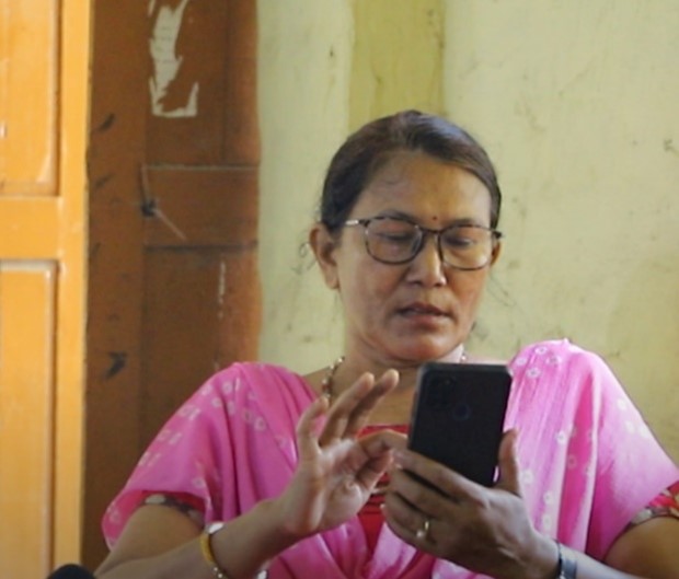 A female teacher in Nepal in a staff room watching a video on a mobile phone