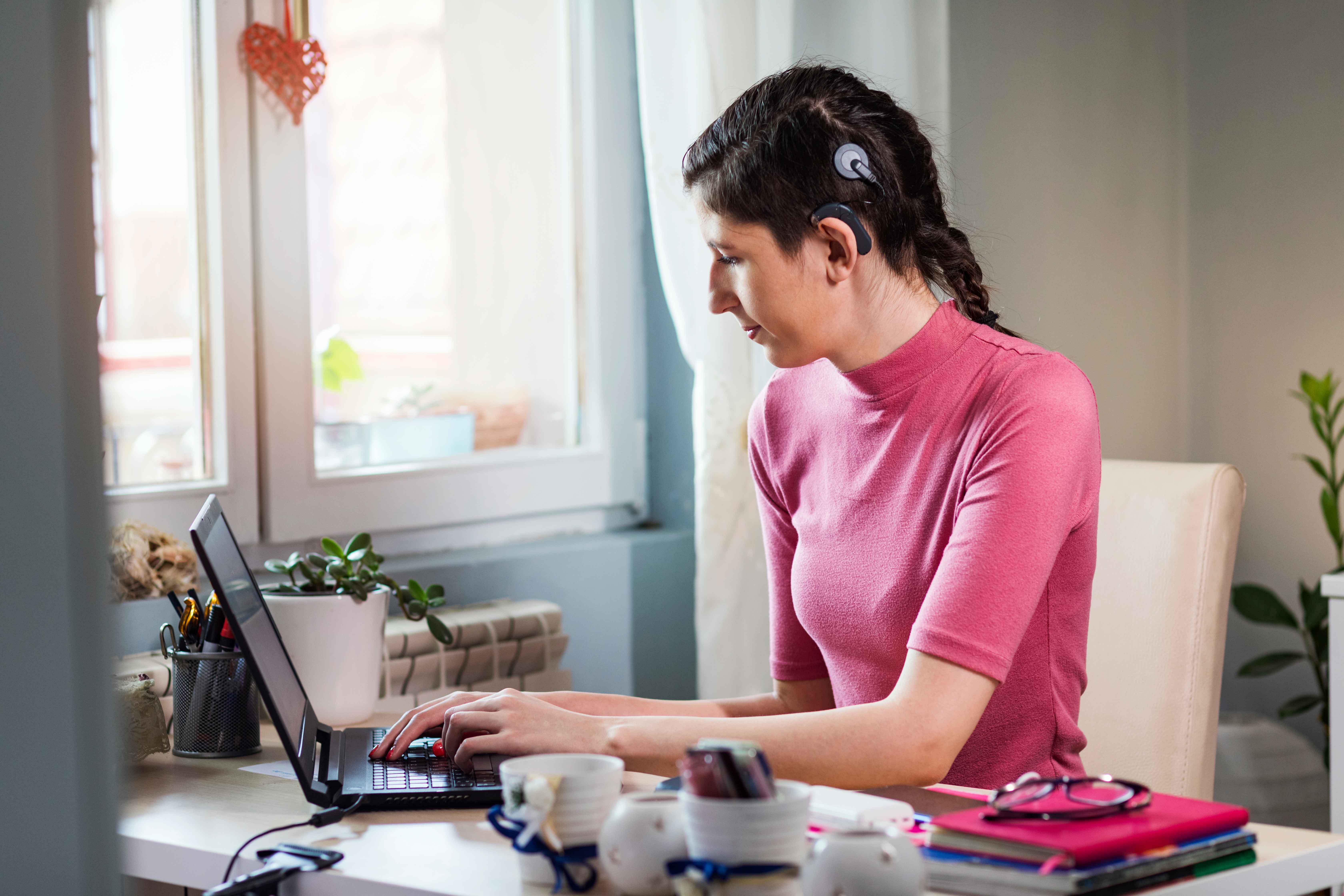 Young woman with cochlear implant studying at home.