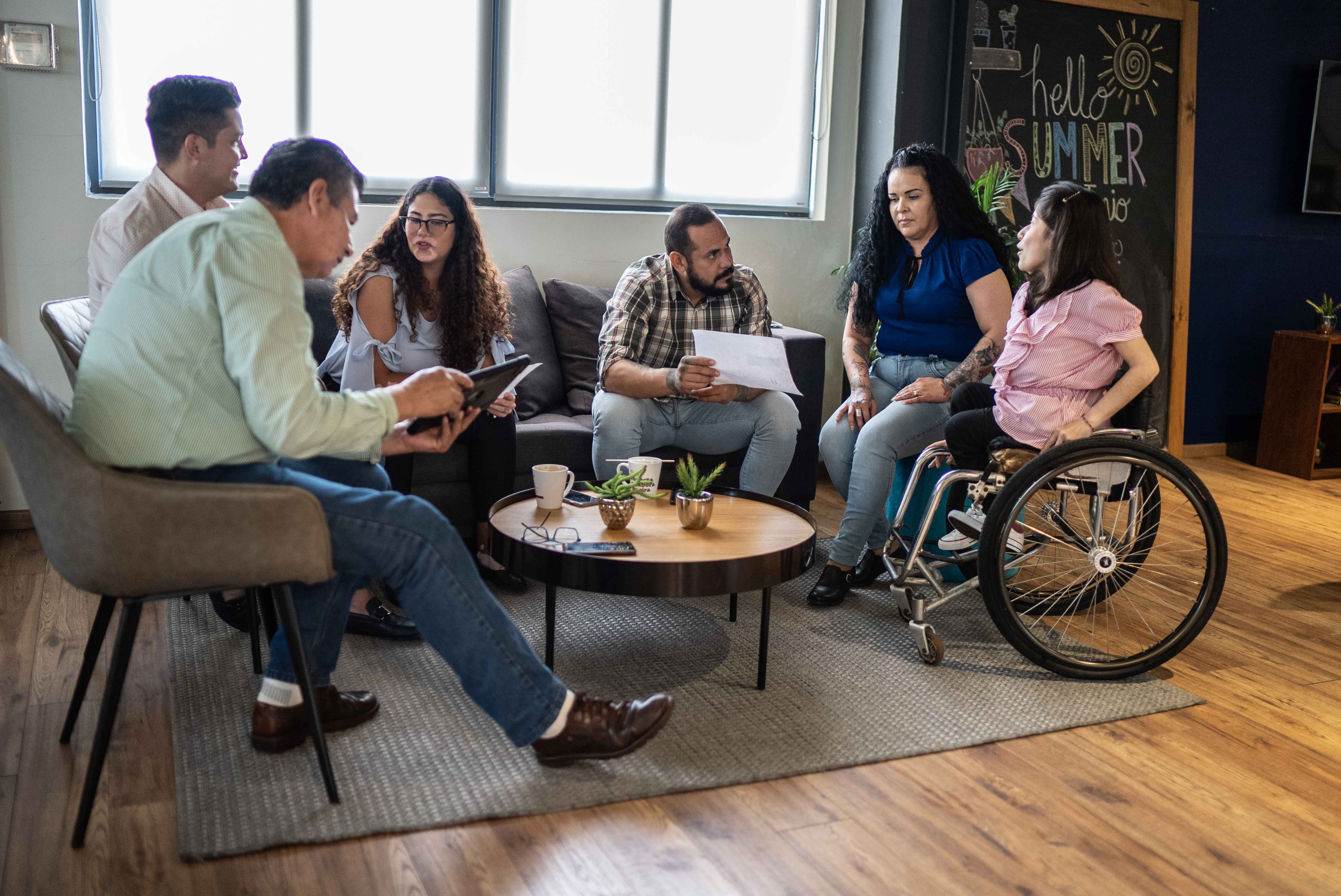 Six people sat in a circle around a small table working as a group
