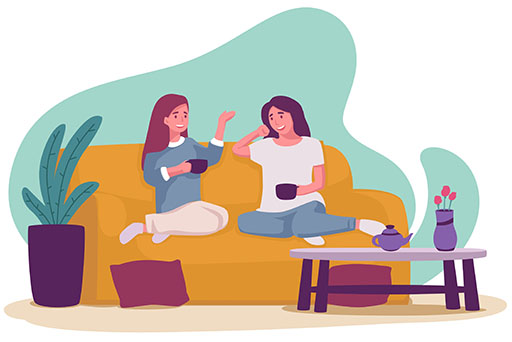 Two young women sitting on a sofa enjoying a drink of tea together.