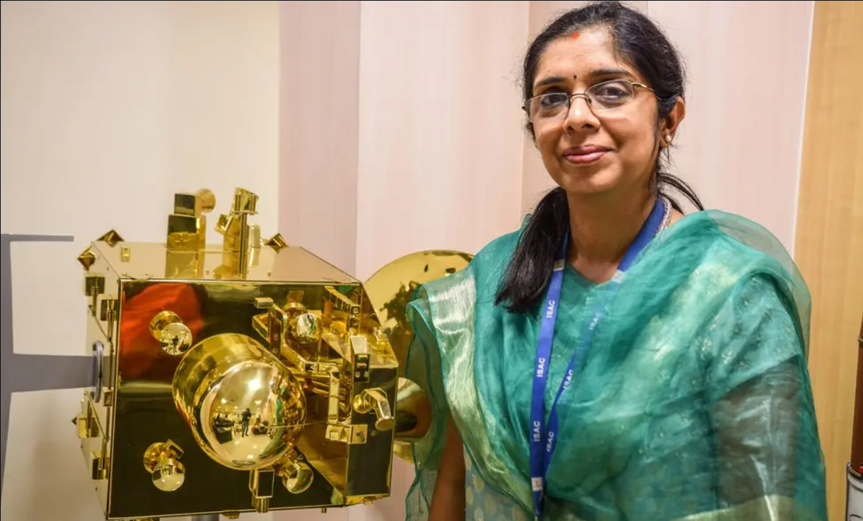 Nandini Harinath, an Indian woman, stood next to a golden piece of equipment.