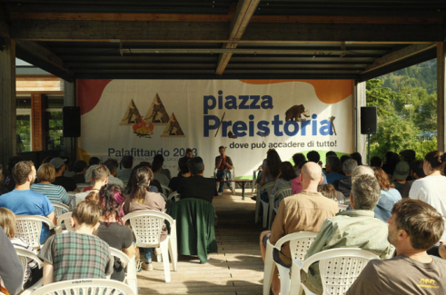 A group of people meeting under a roof structure outdoors.