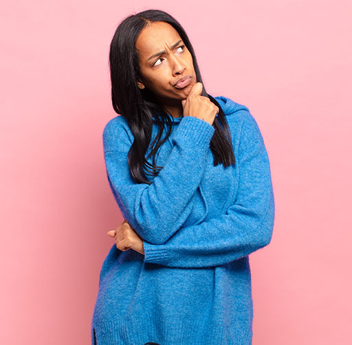 A young woman standing with her head to one side and her hand on her chin, thinking of something.