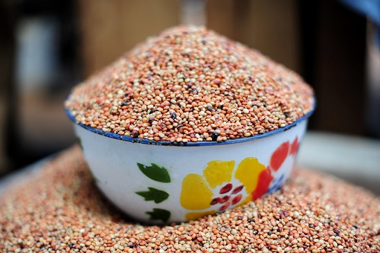 The image shows a colorful bowl of sorghum seeds at Sawla market in Ghana.