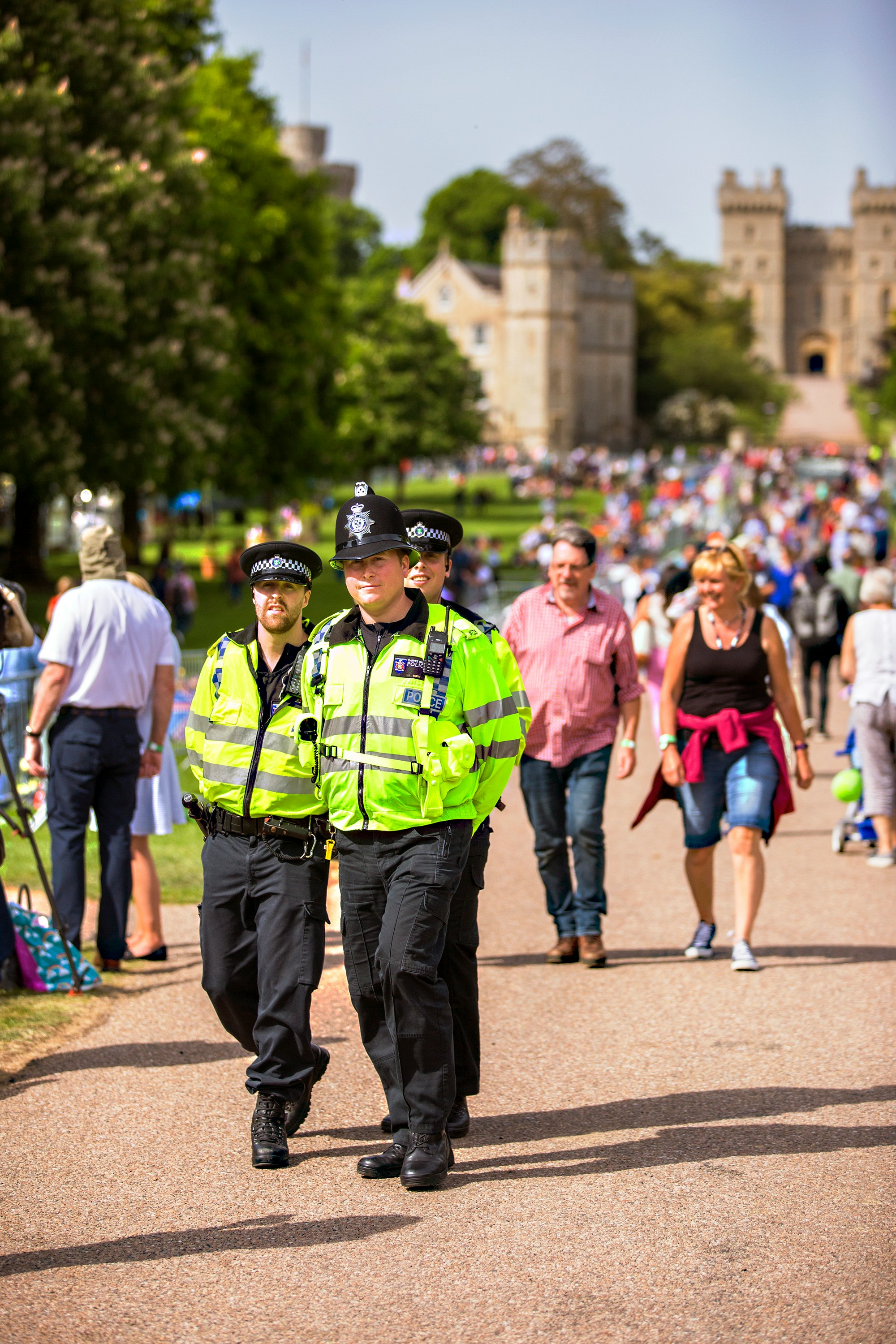 An image of three officers in full uniform walking along a busy path surrounded by trees and a castle in the background