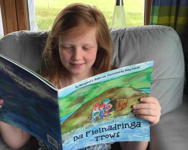 Girl reading picture book in Scots