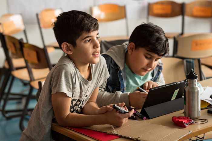 Two young boys working together at a school desk.