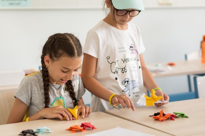 Two children sitting at a desk playing a board game.