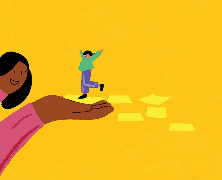 A child standing on a supportive human hand.