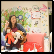 Teacher gesturing while holding soft toys.
