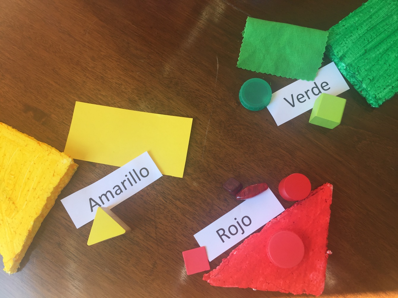 Table top with items arranged by colour, and labelled with colour in foreign language.