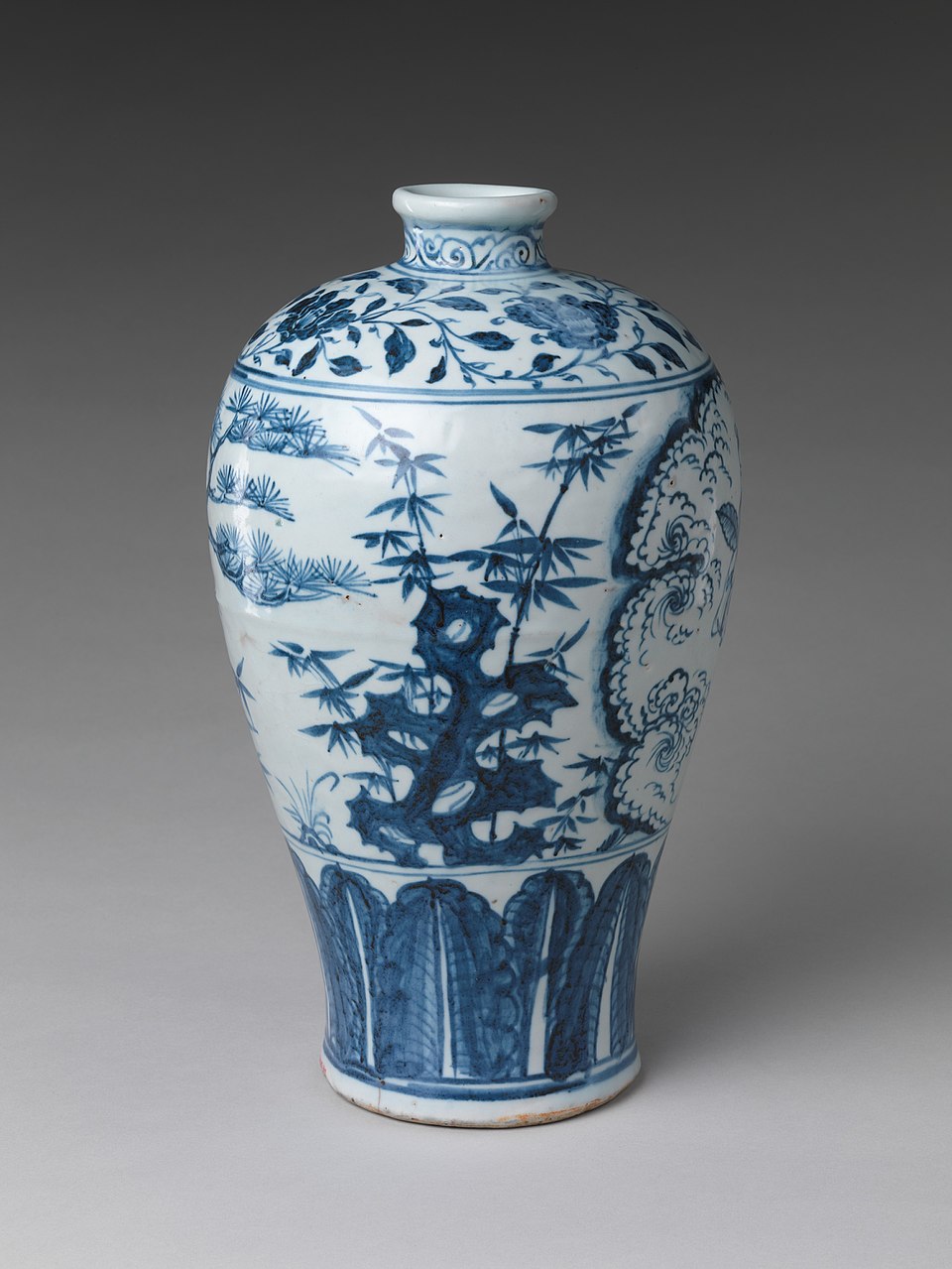 Front view of a tall blue-and-white porcelain vase with a short neck and rounded shoulder. Underglaze cobalt designs show bamboo leaves and stalks around a porous scholar’s rock, with scrolling cloud motifs and decorative bands at the neck, shoulder, and lower body.
