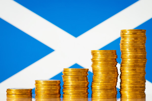A photo of columns of coins against the background of the Scottish flag.