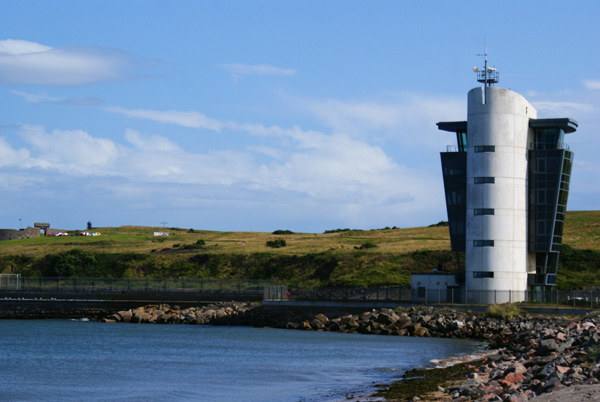 A photo of a five-storey concrete building at the water’s edge.