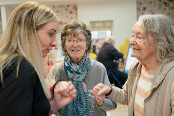A photo of a younger woman holding the hands of two older women.